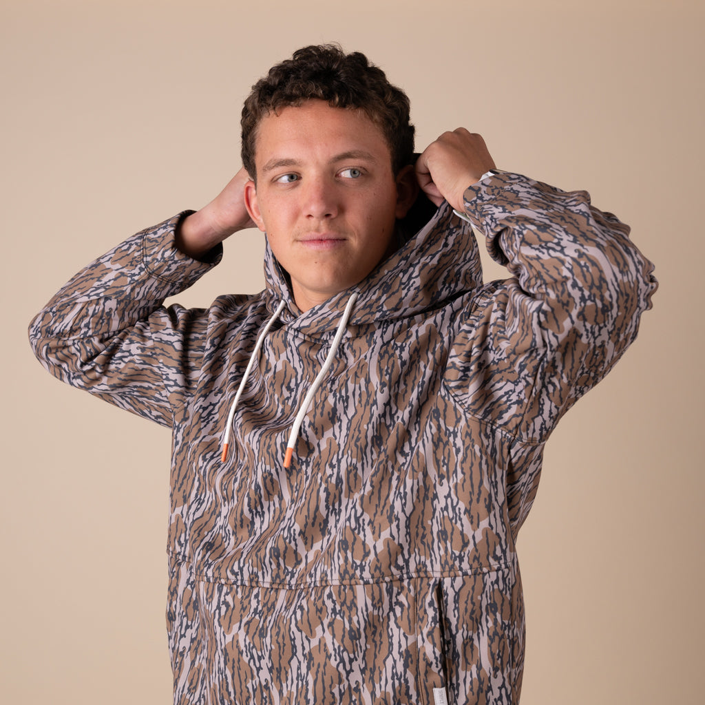Person wearing a patterned hoodie against a beige background