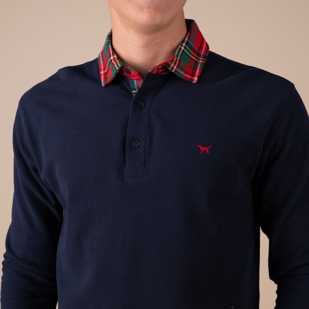 Man wearing a navy long sleeve polo with a red plaid collar.