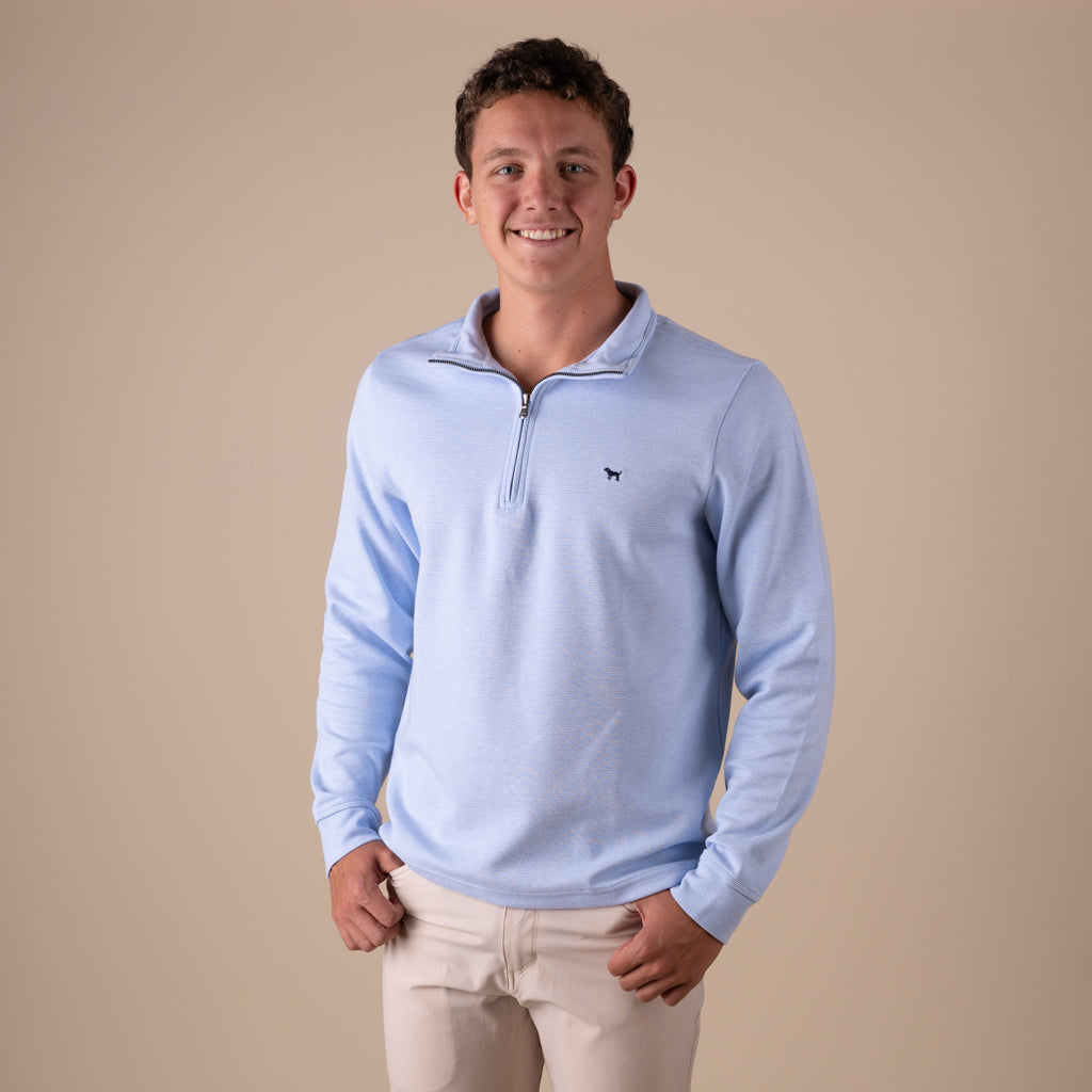 Man wearing a light blue pullover with a small logo on a beige background