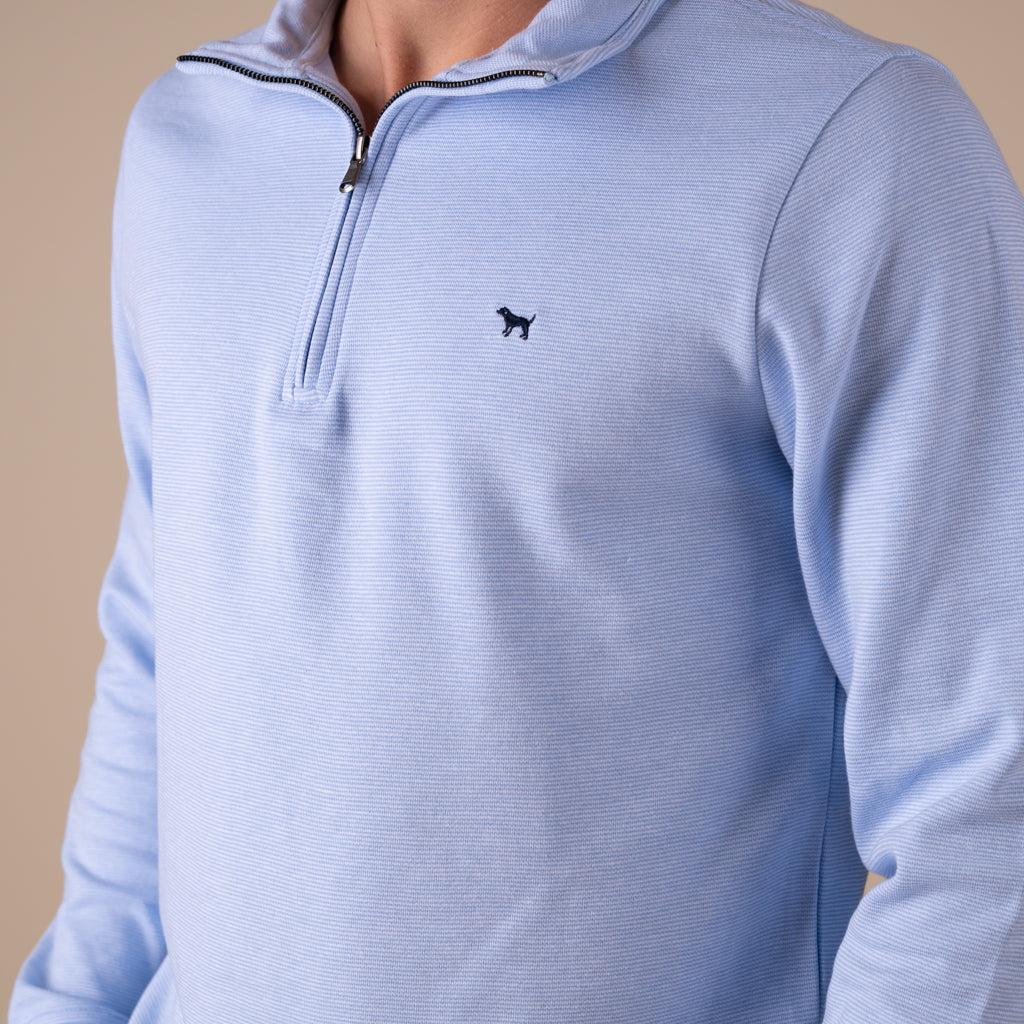 Light blue pullover with a small logo on a beige background