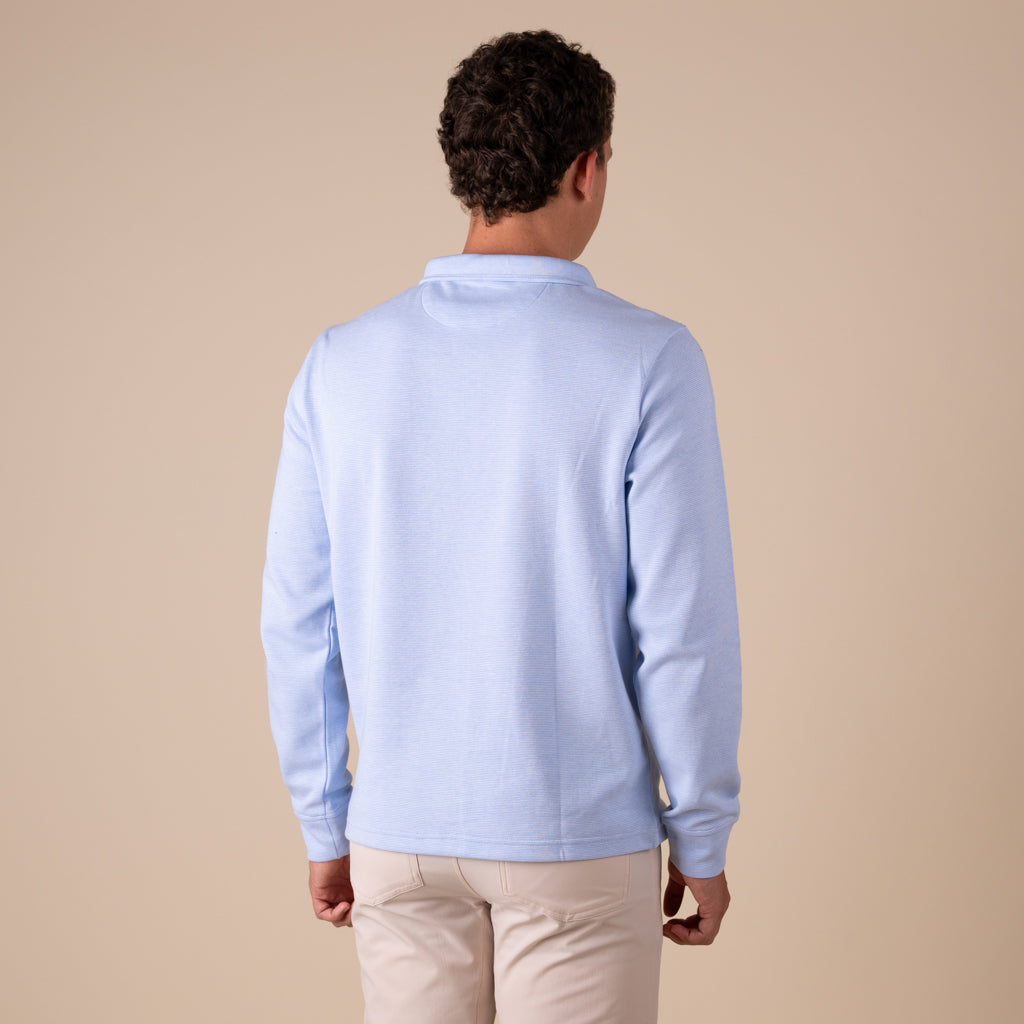 Man wearing a light blue sweater and beige pants against a beige background