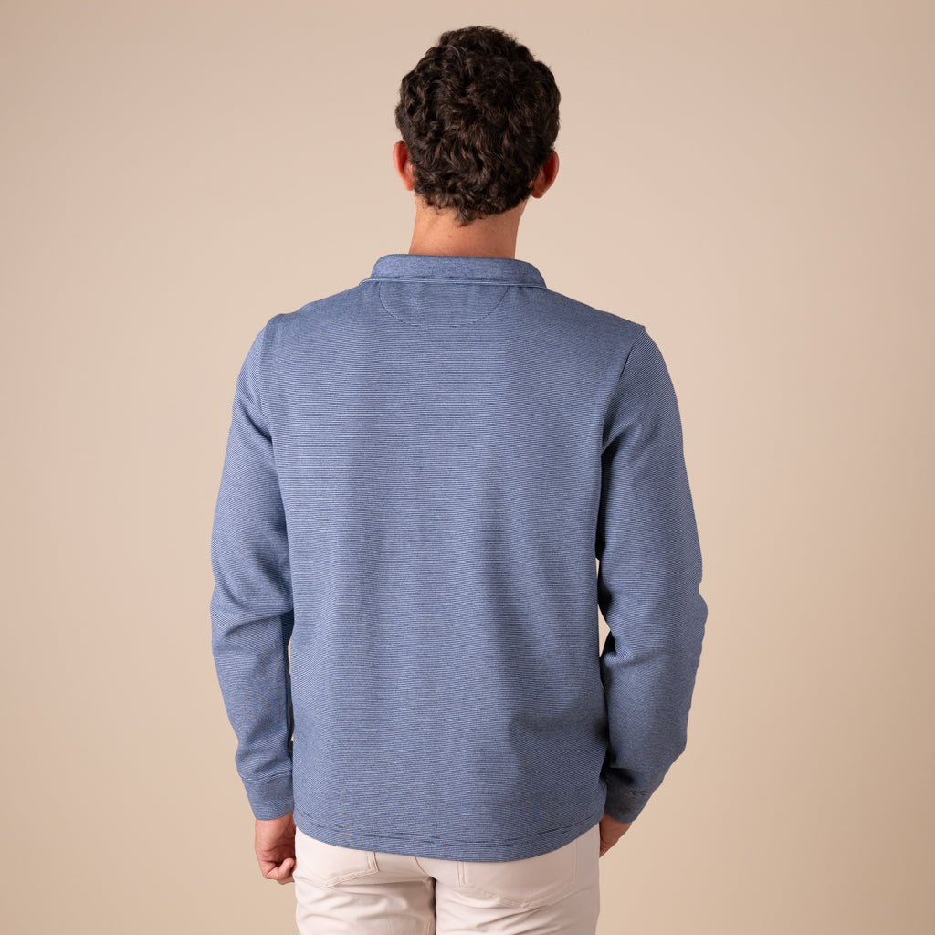 Man wearing a blue sweater from behind on a beige background