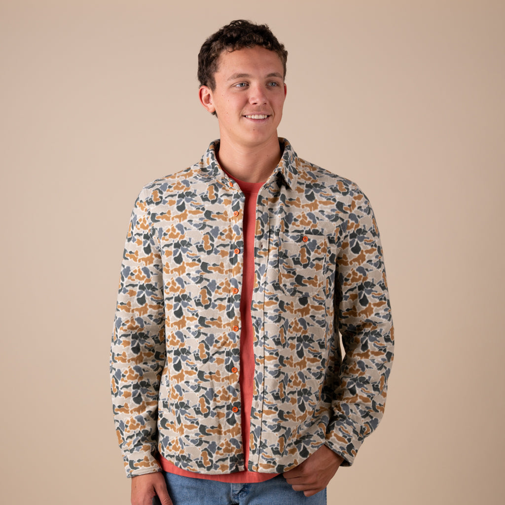 Man wearing a camo shacket with a beige background