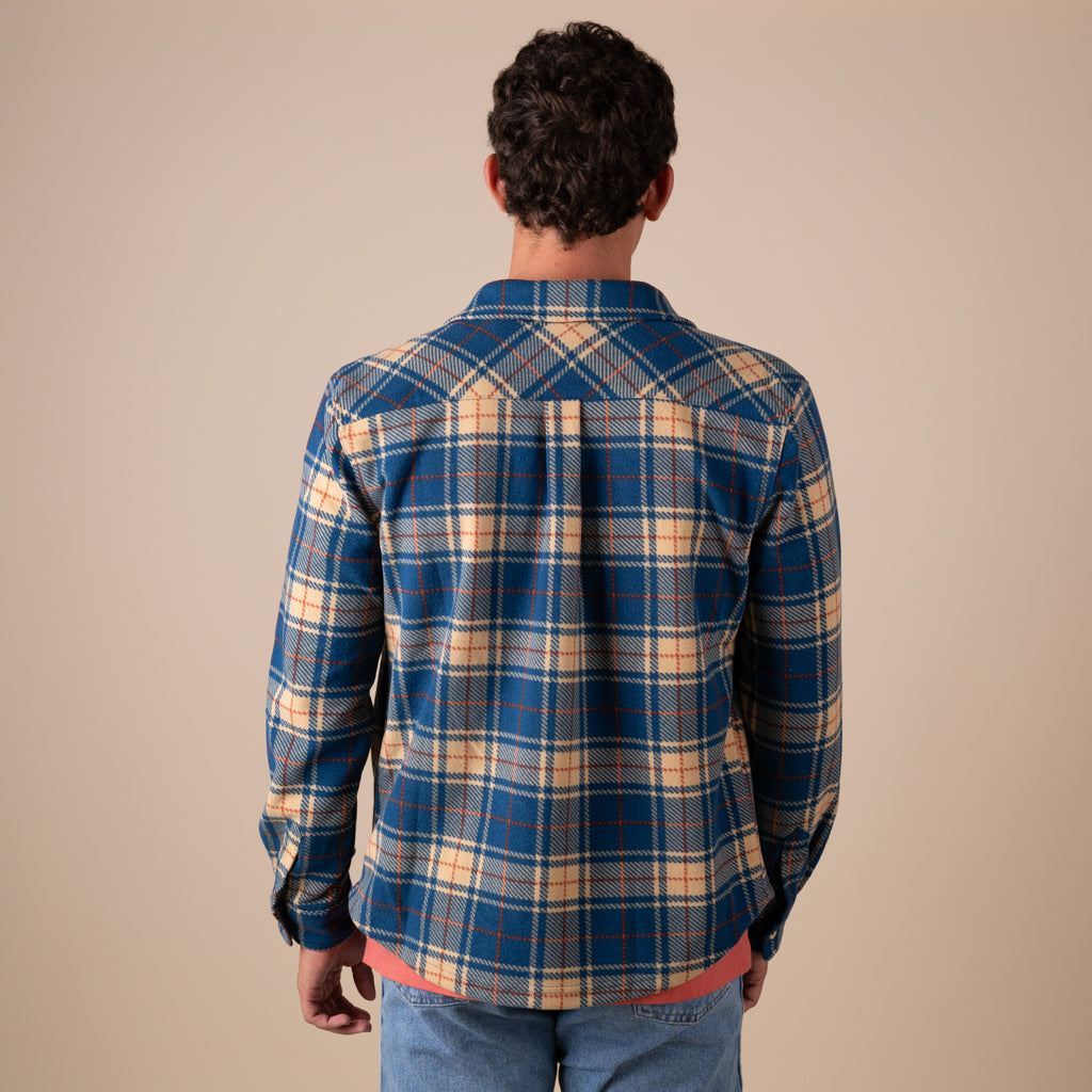 Man wearing a blue and beige plaid shirt against a beige background