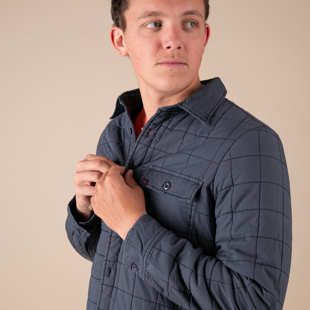 Man wearing a quilted jacket against a beige background
