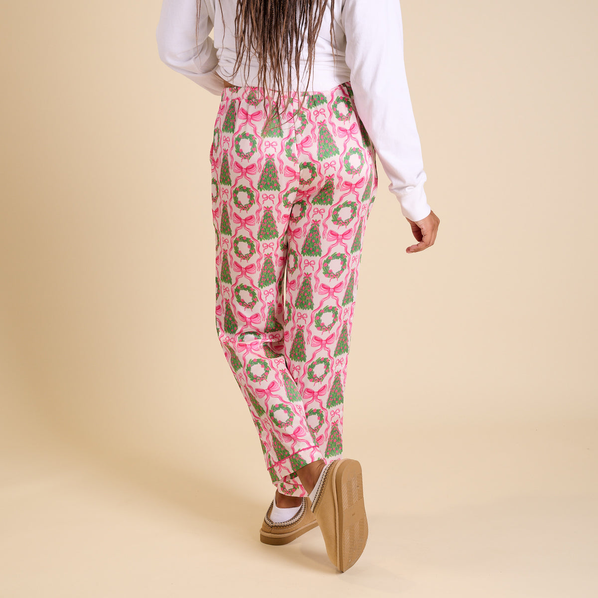 Back view of women’s Christmas print pajama pants with pink bows and green wreaths.