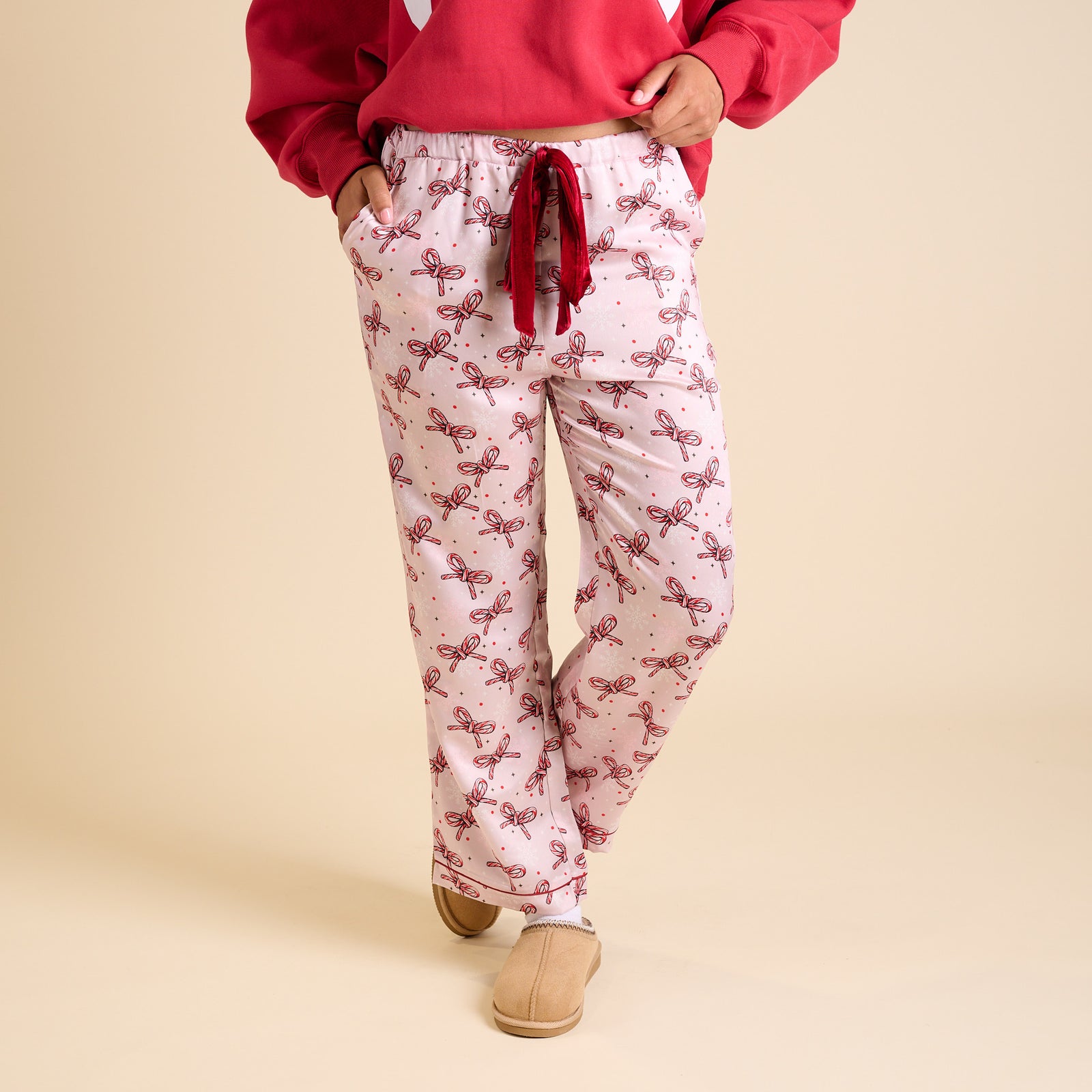 Front view of pink holiday pajama pants with allover candy cane bow design.