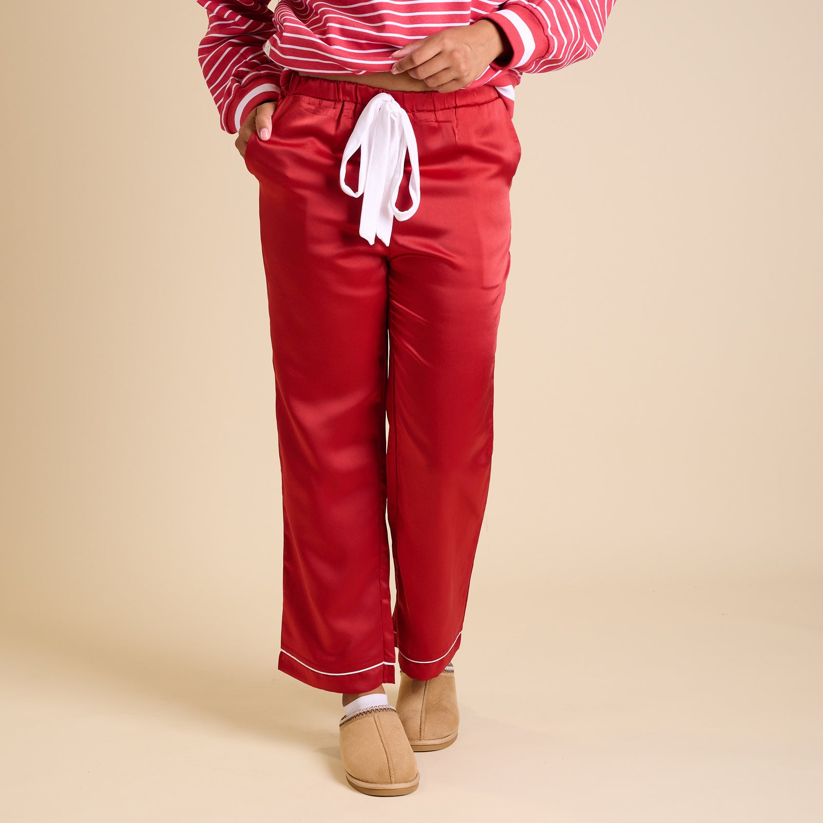 Front view of red satin pajama pants with white drawstring and straight-leg fit.