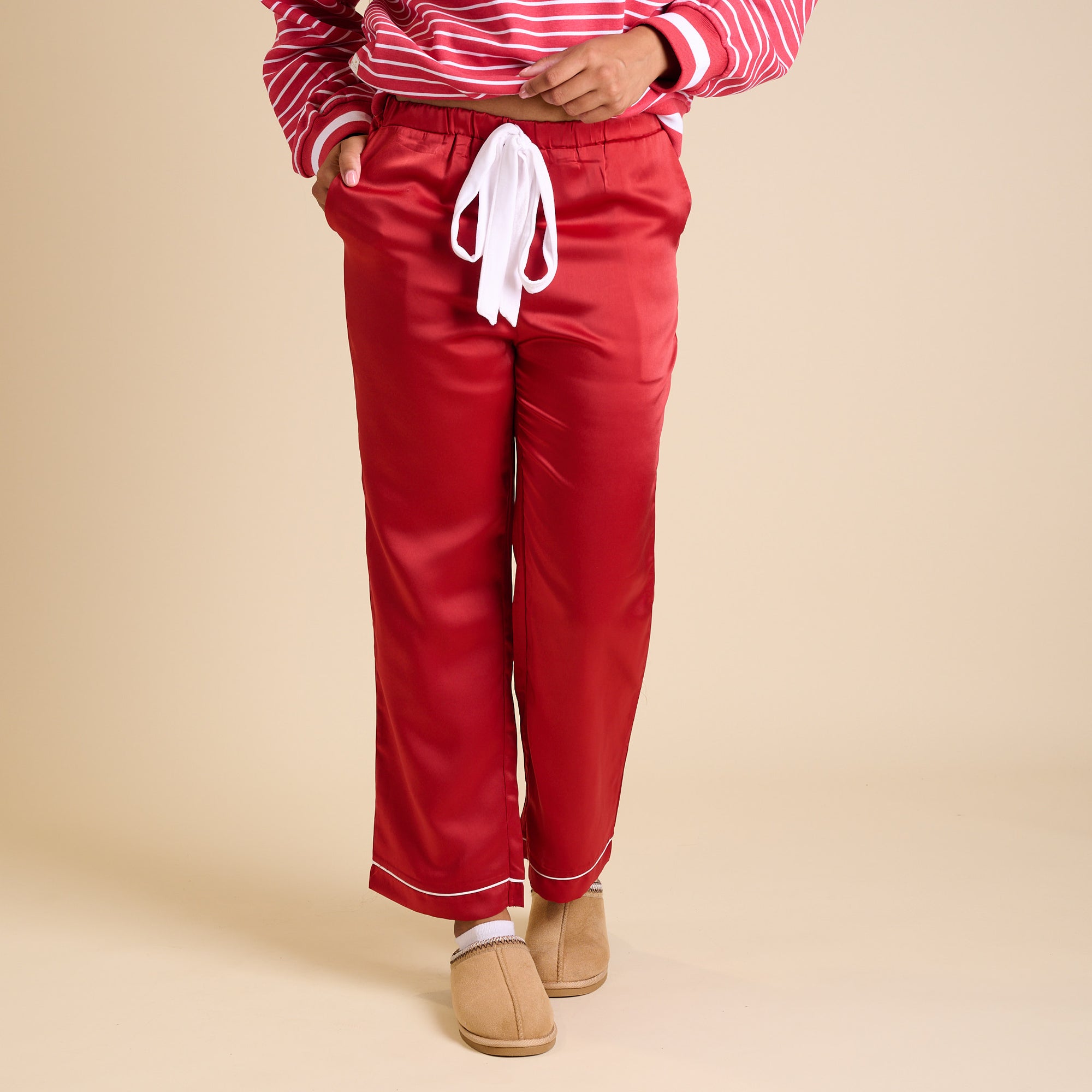 Front view of red satin pajama pants with white drawstring and straight-leg fit.