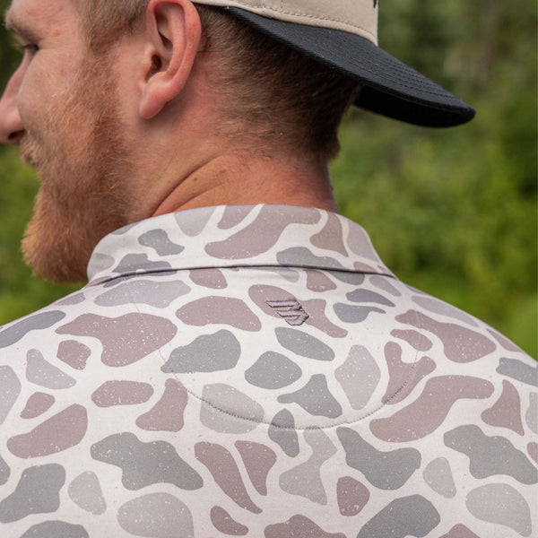 Close-up of a camo polo shirt with a blurred green background