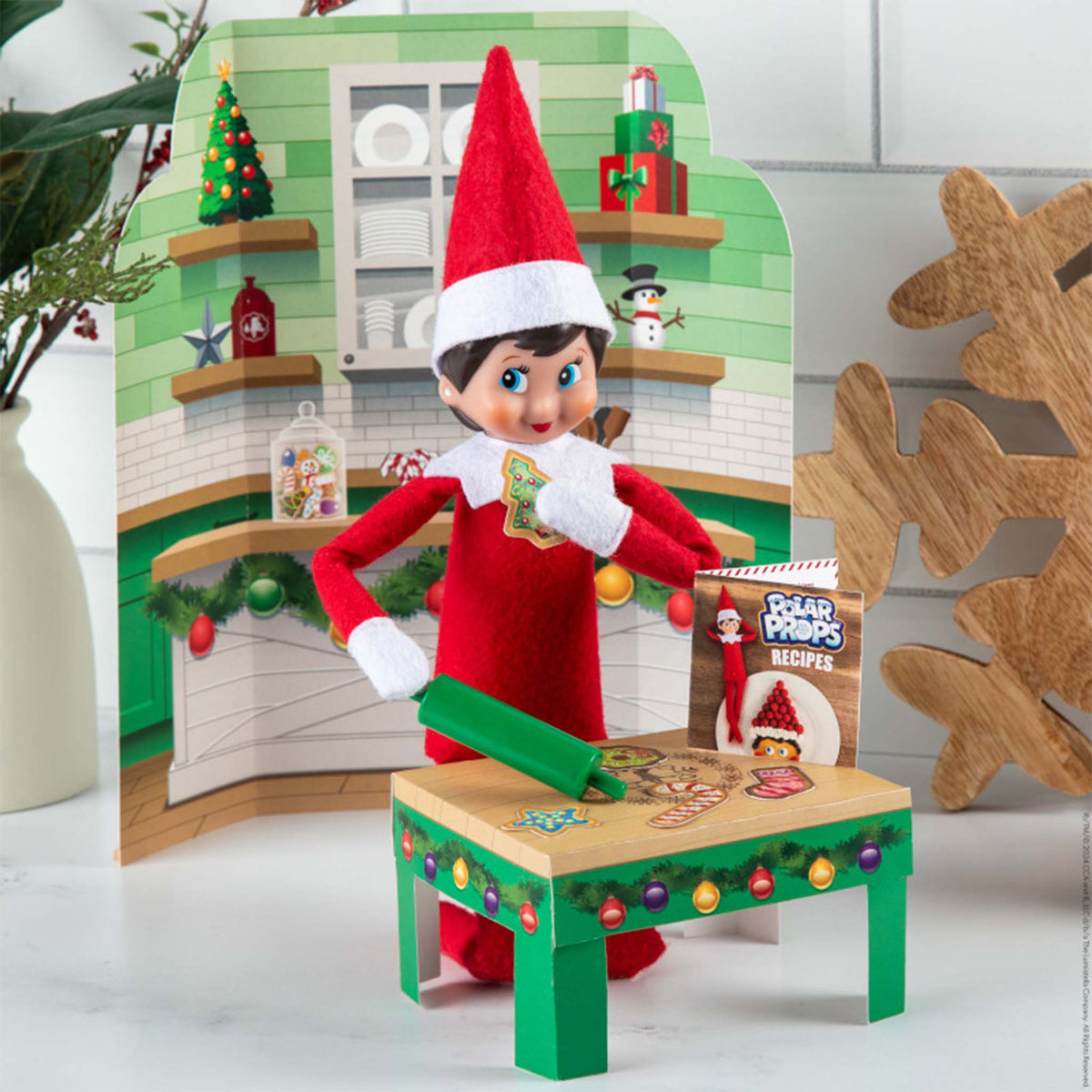 Elf on the Shelf with a kitchen backdrop and cookie sheet