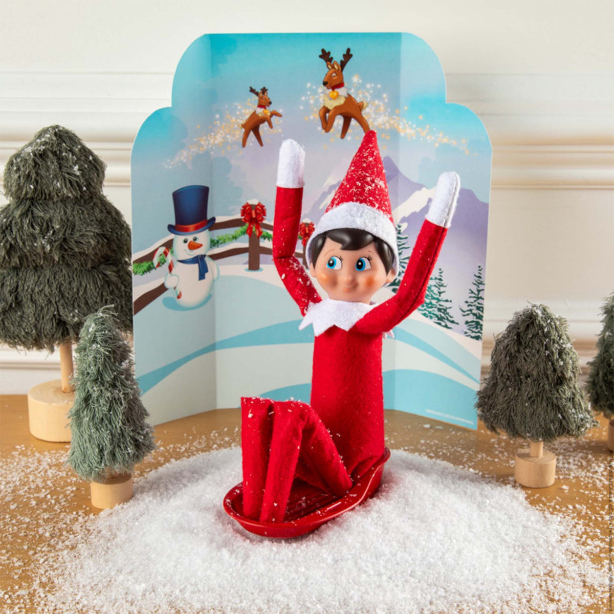 Elf on the Shelf figurine in a red outfit with a snowy background