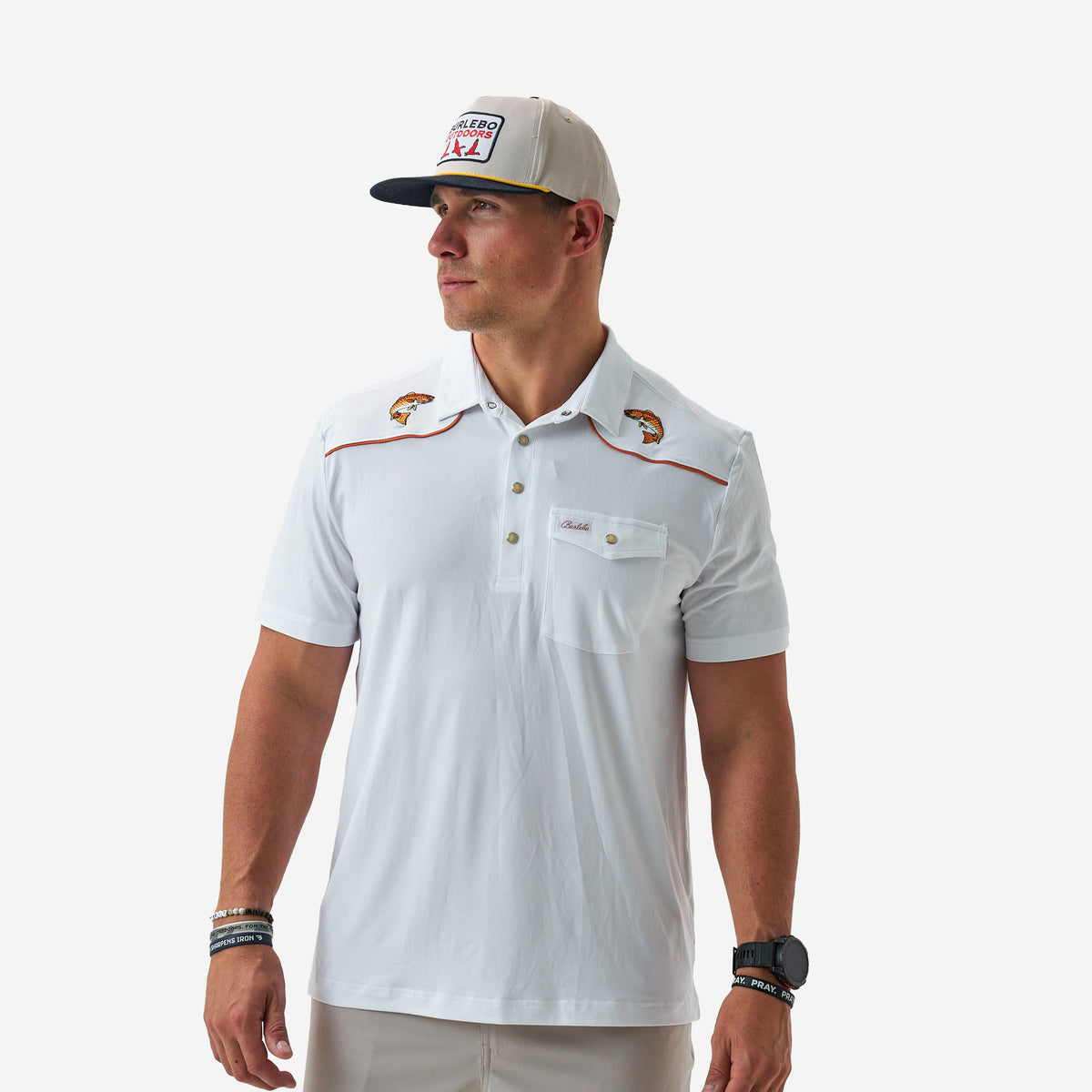 Man wearing a white polo shirt with brand logos and a cap on a white background