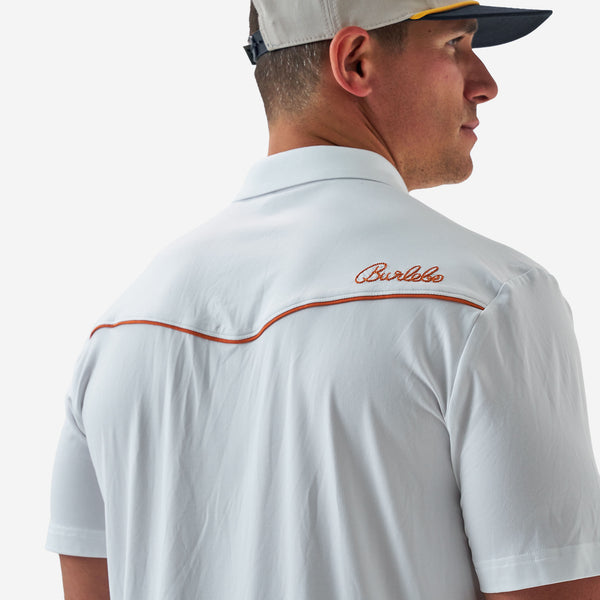 Man wearing a white polo shirt with a brand logo on the back, against a plain background