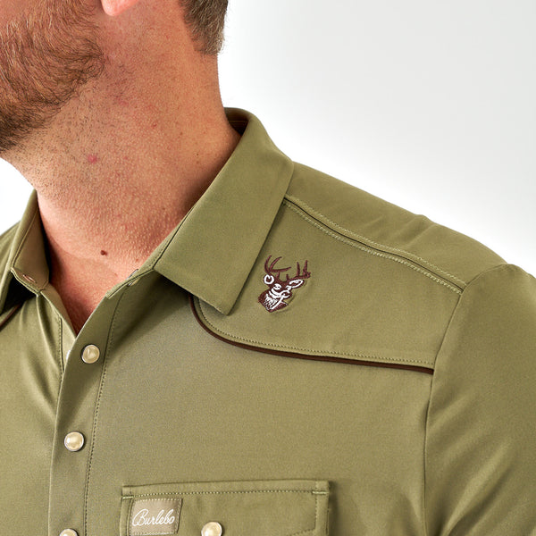 Close-up of a green shirt with a logo on the collar against a white background