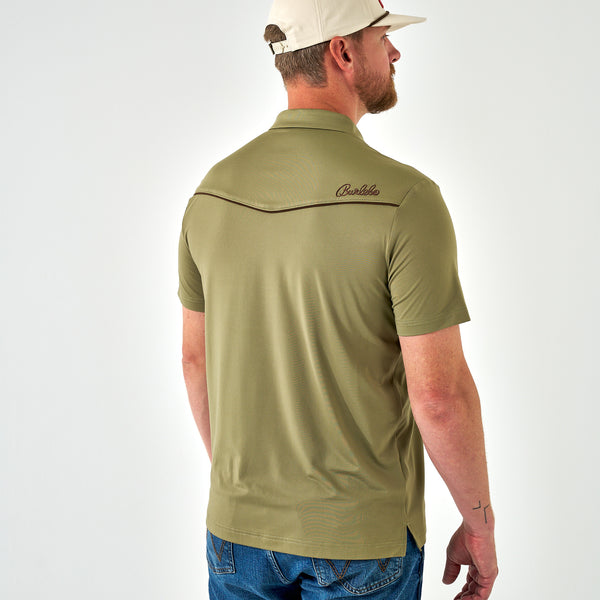 Man wearing a green polo shirt with a visible brand logo on the back, standing against a white background.
