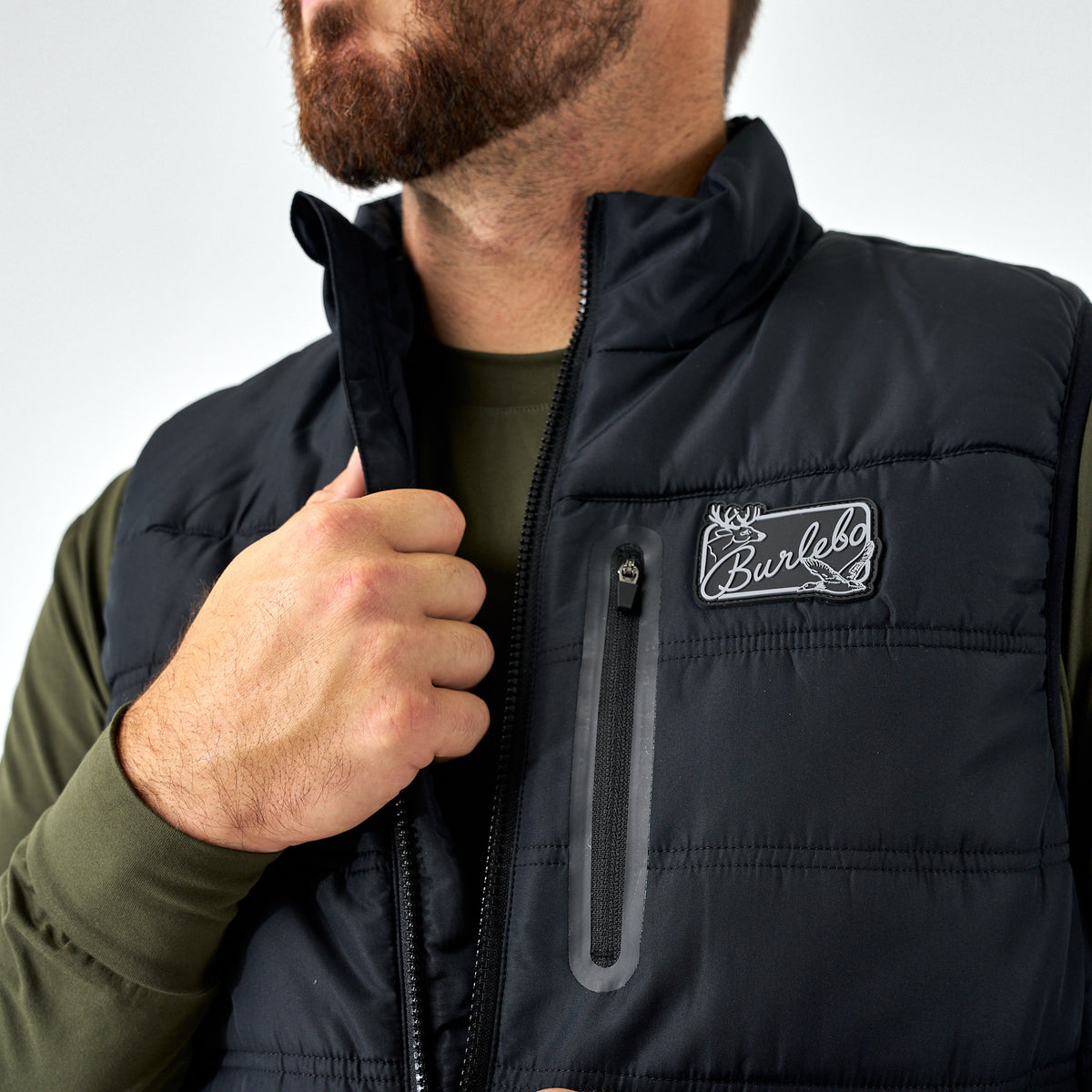 Person wearing a black puffer vest with a brand logo on a white background