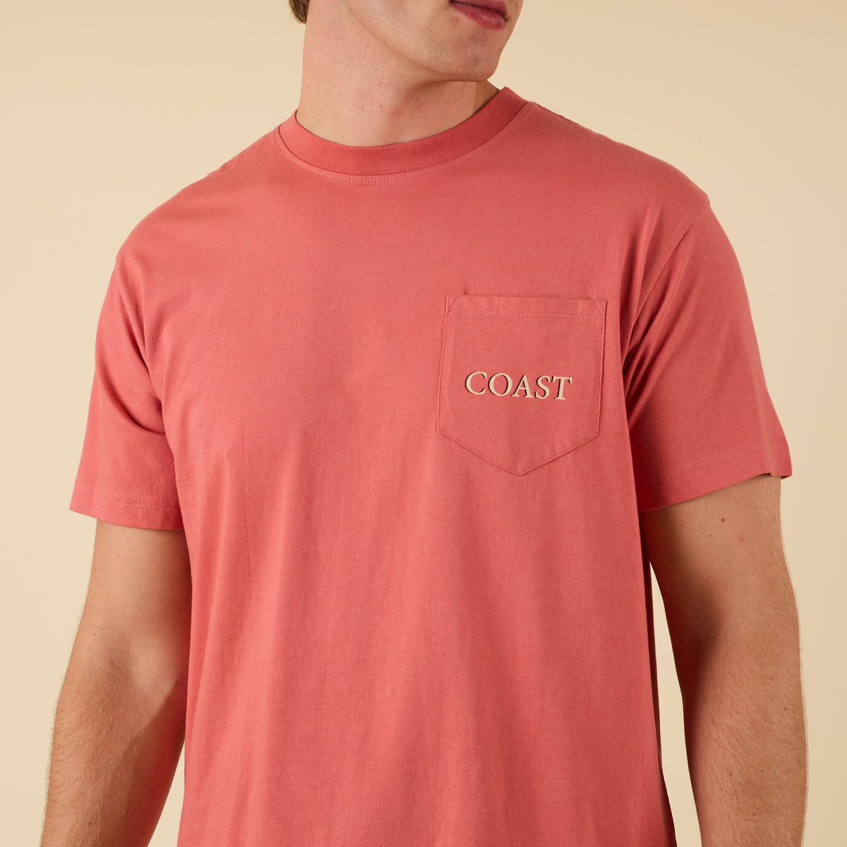 Angled front view of model wearing COAST Always On Point tee in red with chest pocket logo.