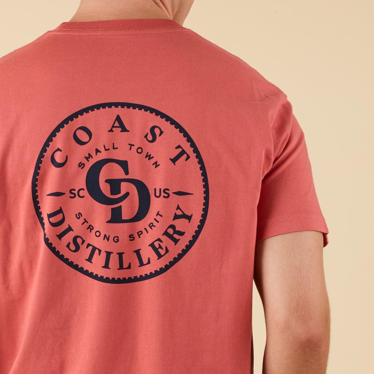 Close-up of COAST Distillery back graphic with circular design and bold navy text.