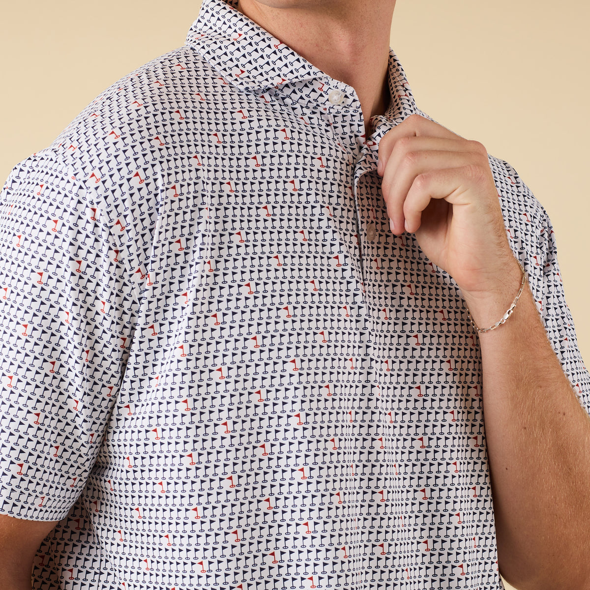 Detailed close-up of navy and red golf flag pattern on white polo shirt fabric, with partial view of collar and buttons.