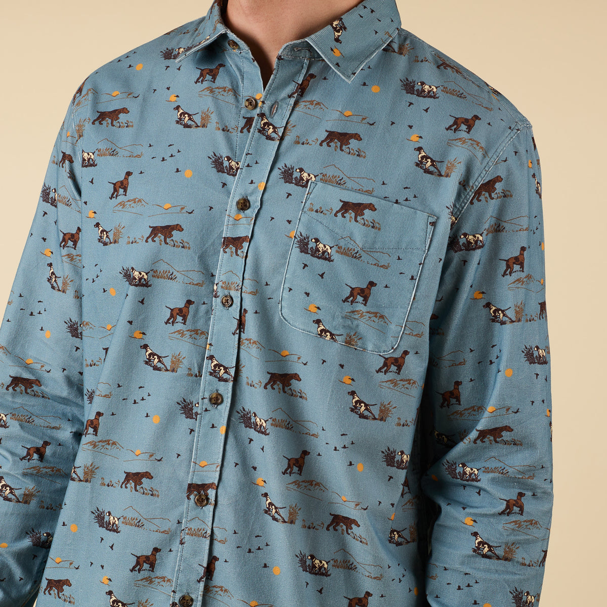 Close-up of blue shirt with hunting dog and field scene print, chest pocket detail.