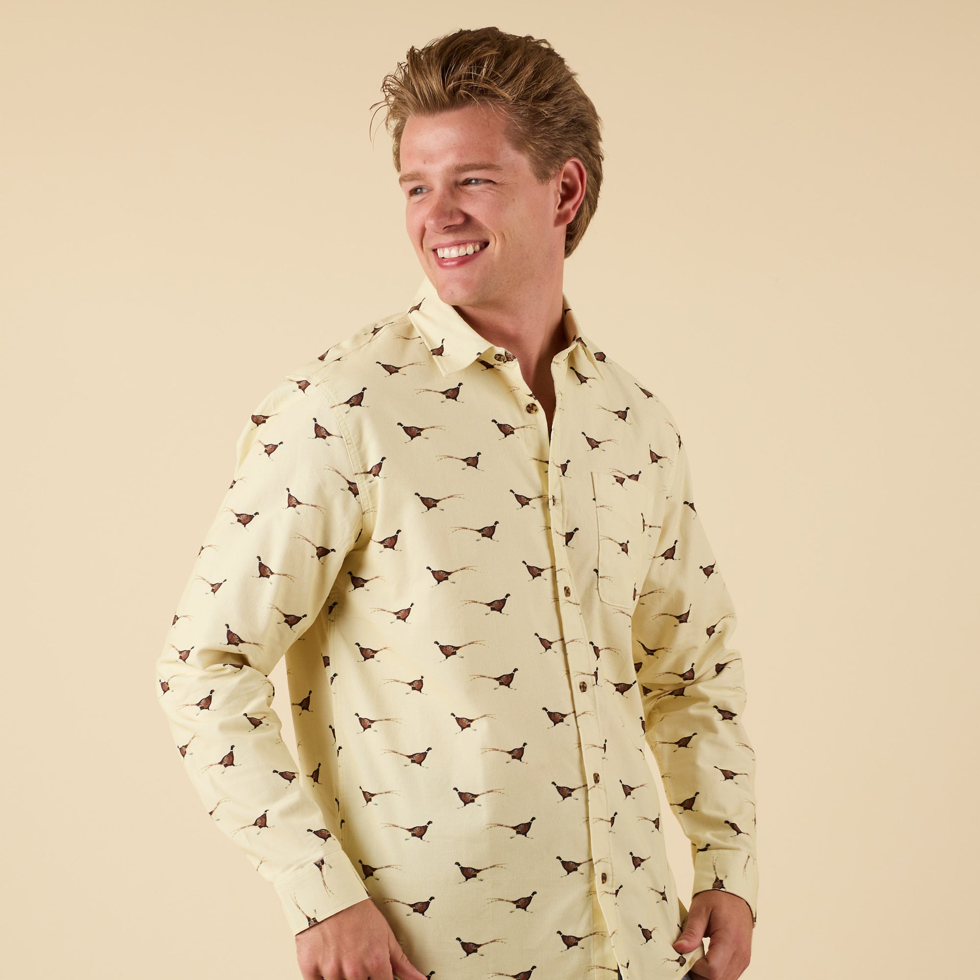 Man wearing yellow long sleeve button-down shirt with pheasant print, front view.