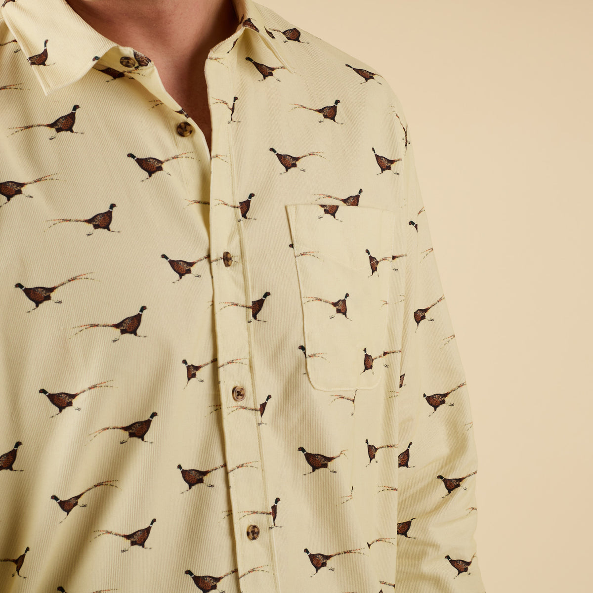 Close-up of yellow pheasant print button-down shirt with chest pocket.