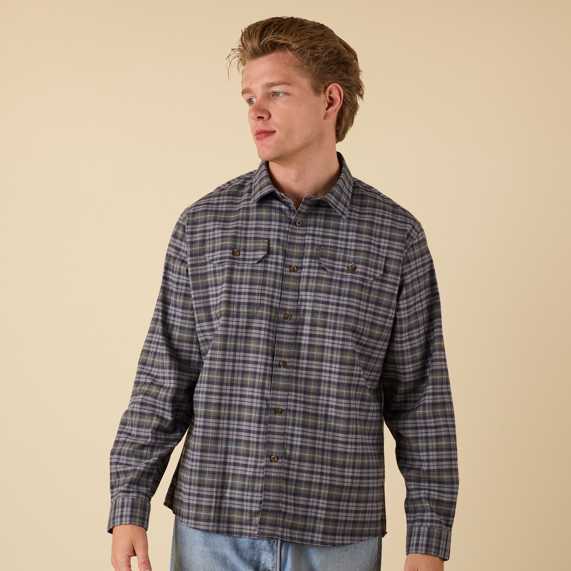 Man wearing a plaid shirt against a beige background