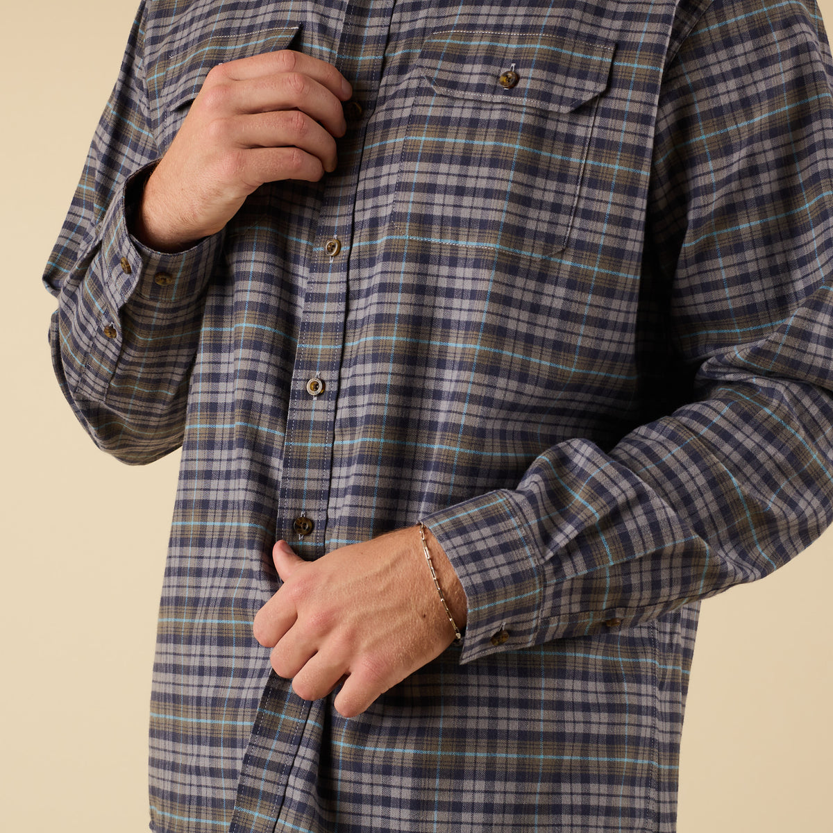 Person wearing a plaid shirt with a beige background