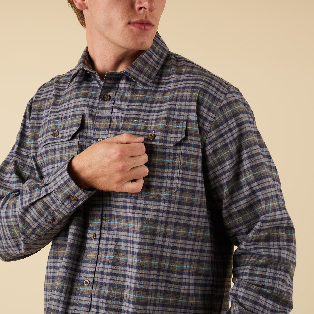 Person wearing a plaid shirt against a beige background
