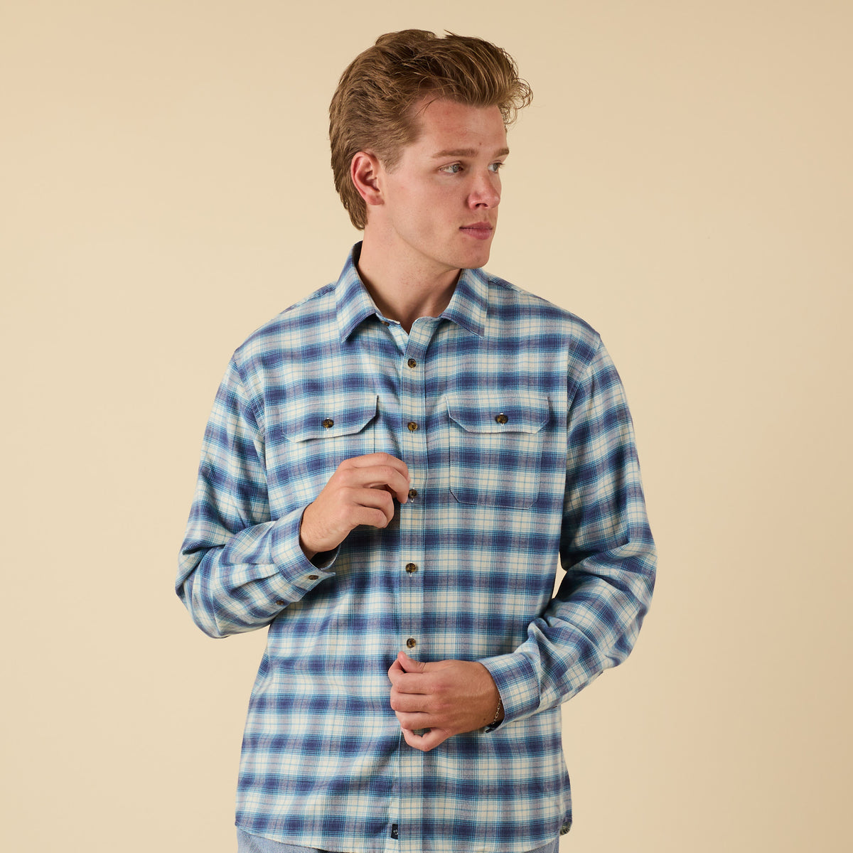 Man wearing a blue plaid shirt against a beige background
