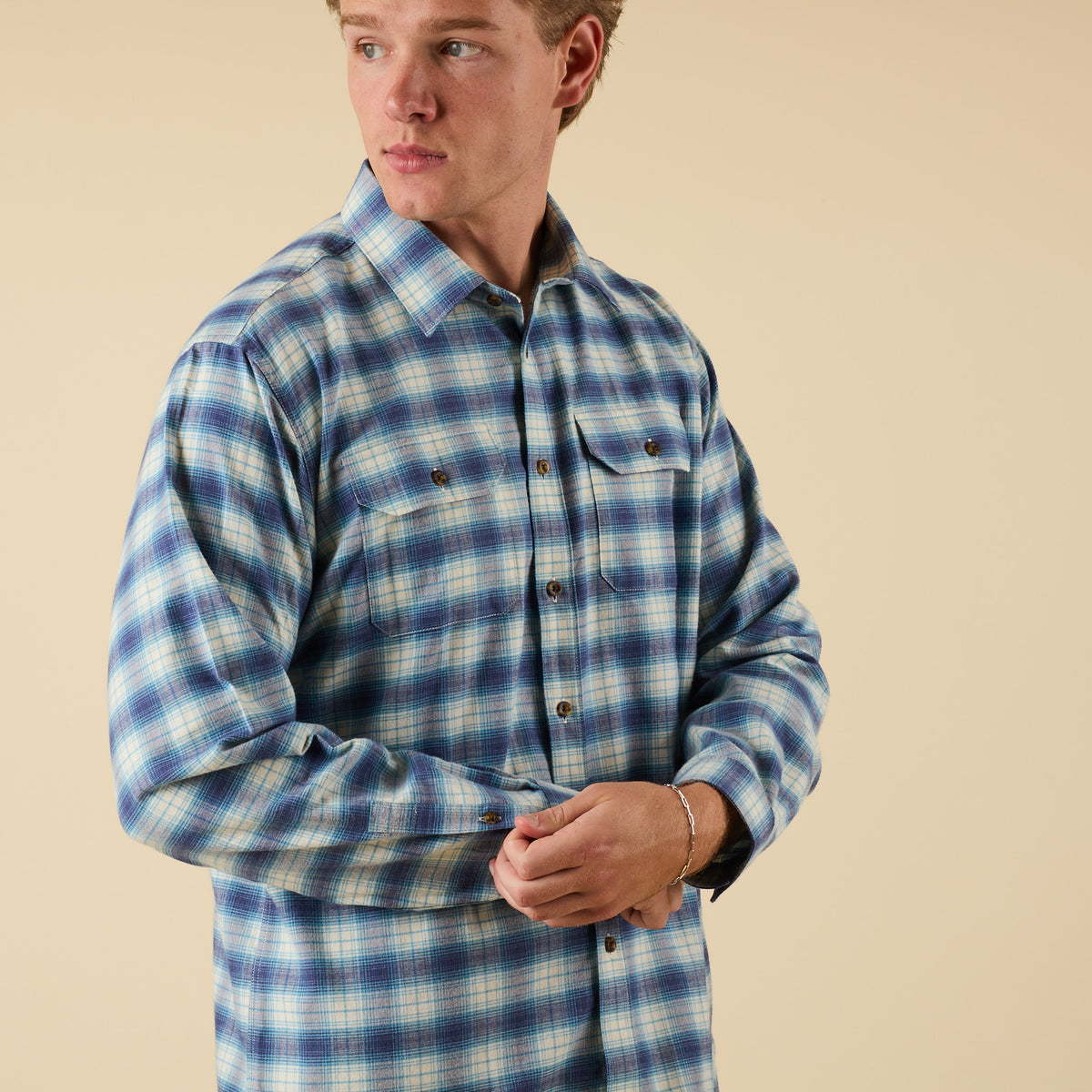 Man wearing a blue and white plaid shirt against a beige background