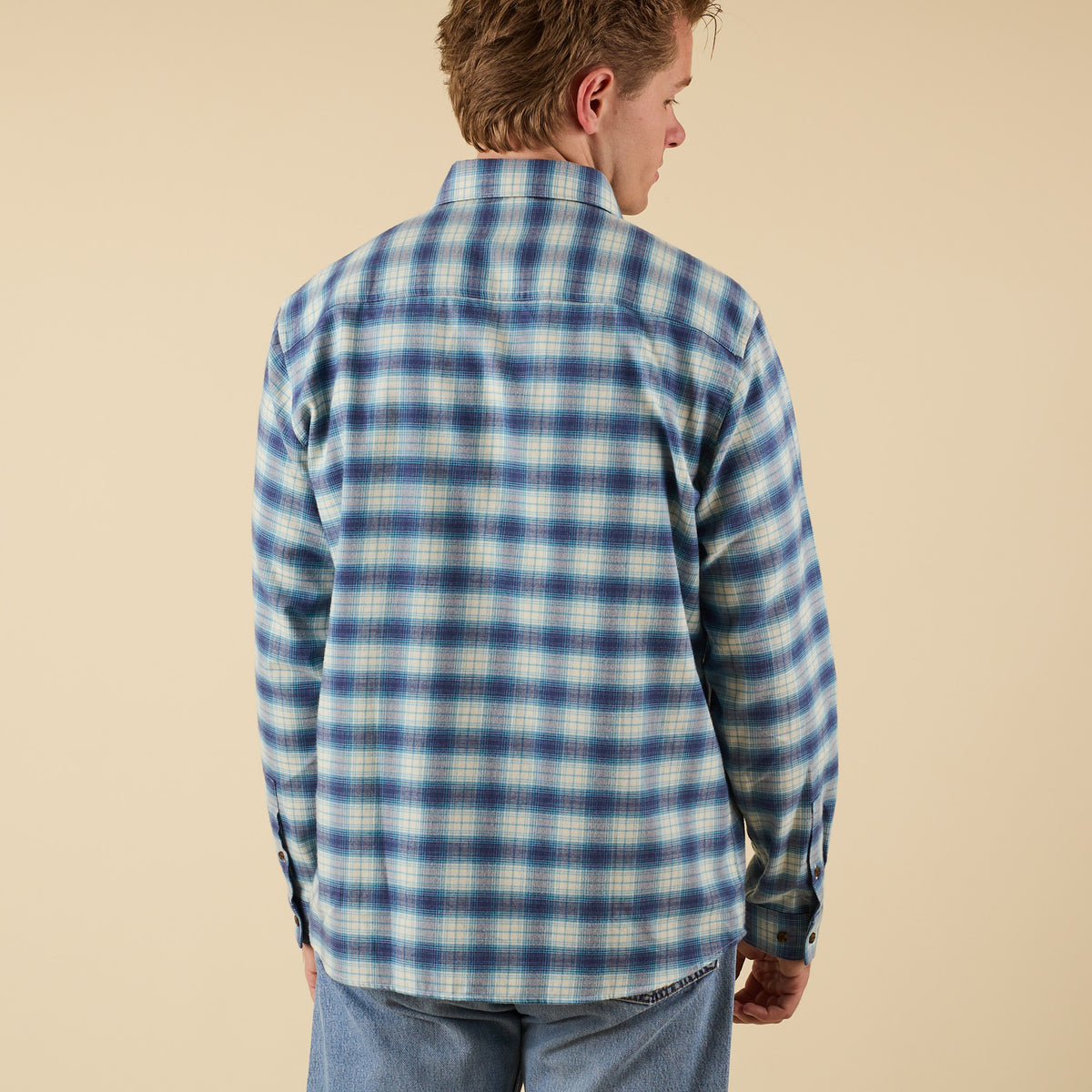 Man wearing a blue and white plaid shirt against a beige background
