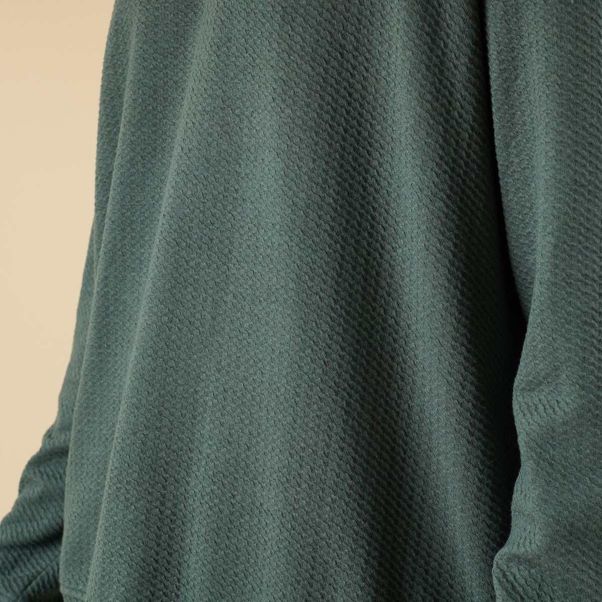 Man wearing a dark green textured quarter zip pullover with a stand collar and relaxed fit.