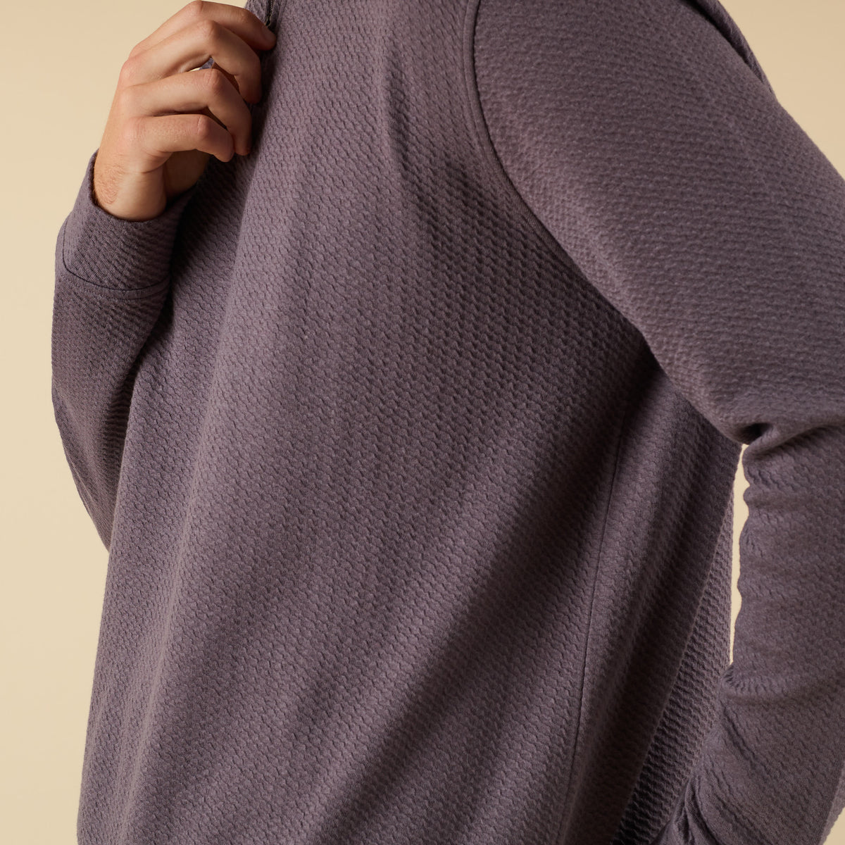 Man wearing a dark grey textured quarter zip pullover with a stand collar and relaxed fit.