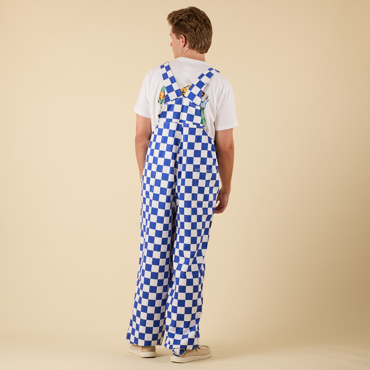 Back view of a man posing for a product photo wearing blue and white checkered overalls.