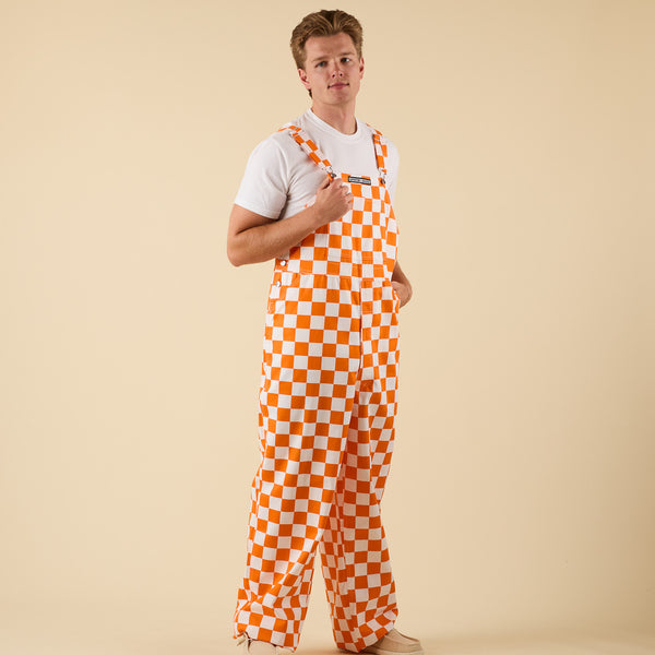 Man posing for a product photo in Orange and white checkered overalls.
