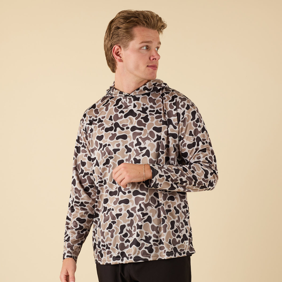 Man wearing a camo performance hoodie with a duck on the back.