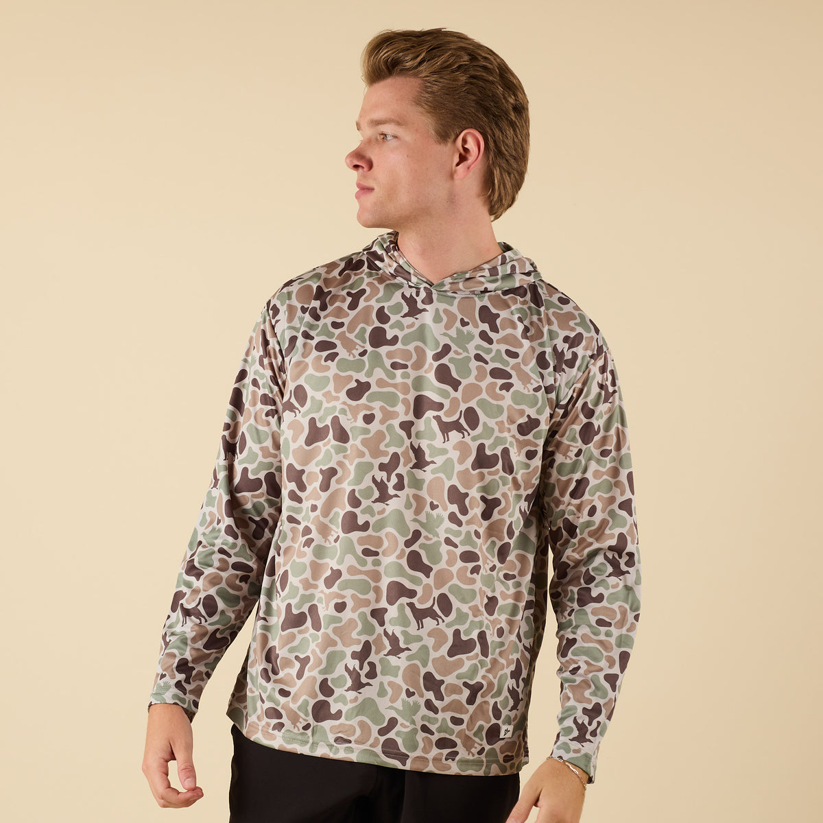 Person wearing a camouflage-patterned hoodie on a beige background