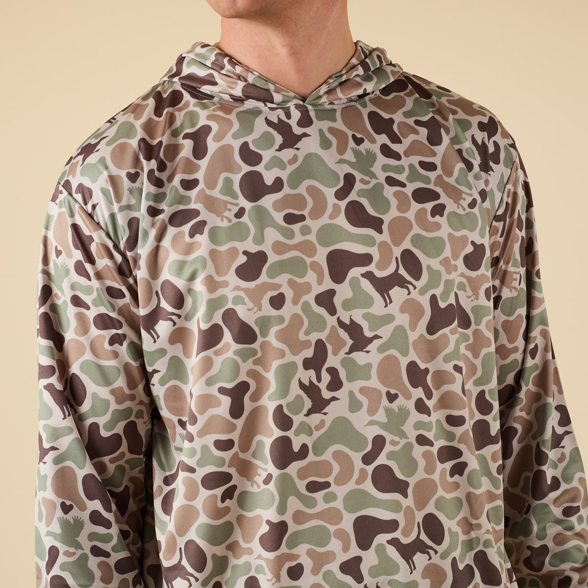 Camouflage-patterned hoodie worn by a person on a beige background