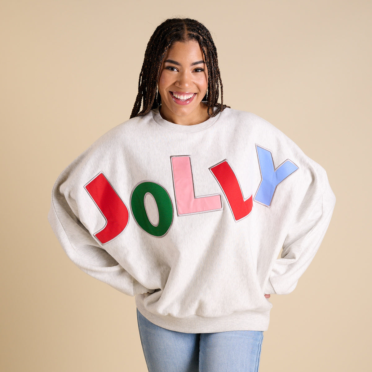 Person wearing a sweater with colorful letters spelling 'JOLLY' on a beige background