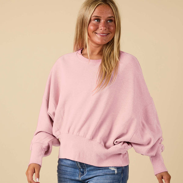Beach Pink crewneck sweatshirt with oversized sleeves, modeled from the side.