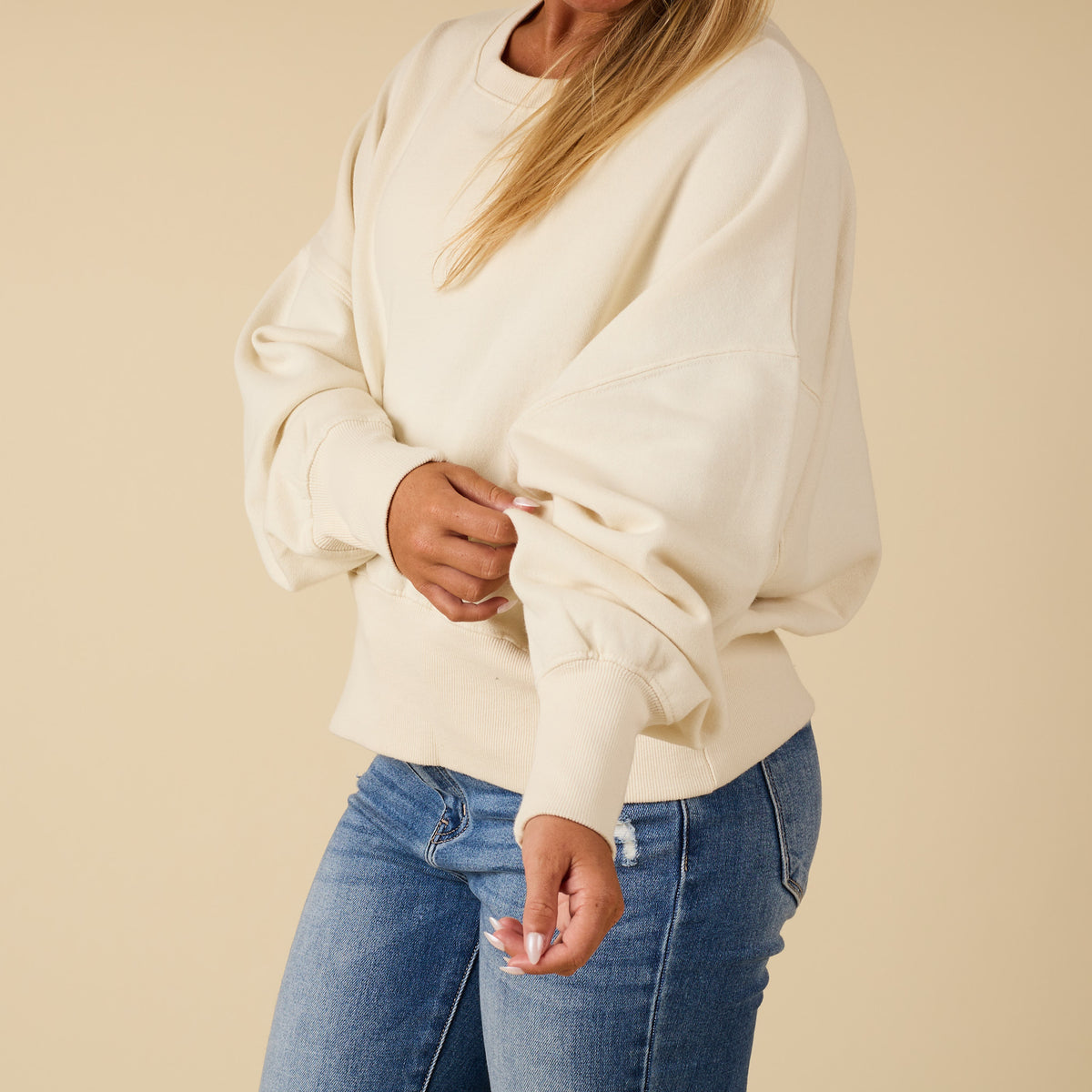 Ivory Youngstown crewneck sweatshirt with relaxed fit and ribbed hem, modeled from the side with model adjusting sleeve.