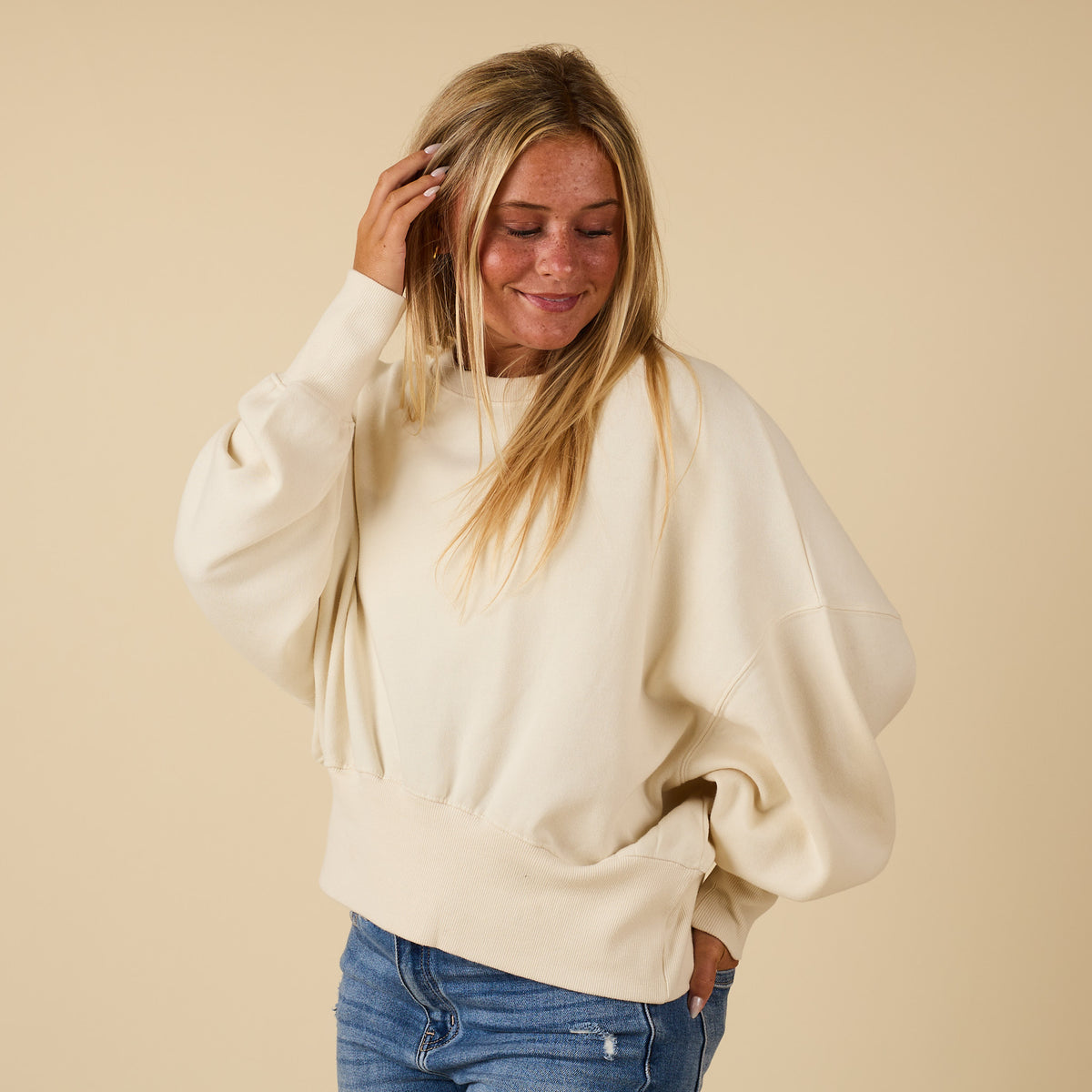Ivory Youngstown crewneck sweatshirt with relaxed fit and ribbed hem, modeled from the side.