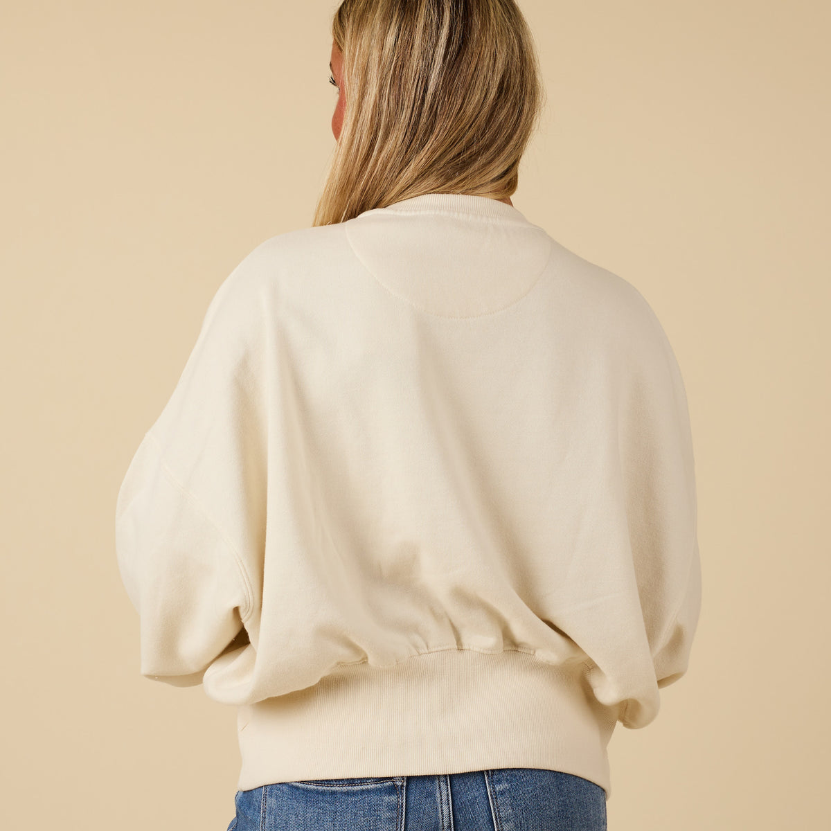 Ivory Youngstown crewneck sweatshirt with relaxed fit and ribbed hem, modeled from the back.