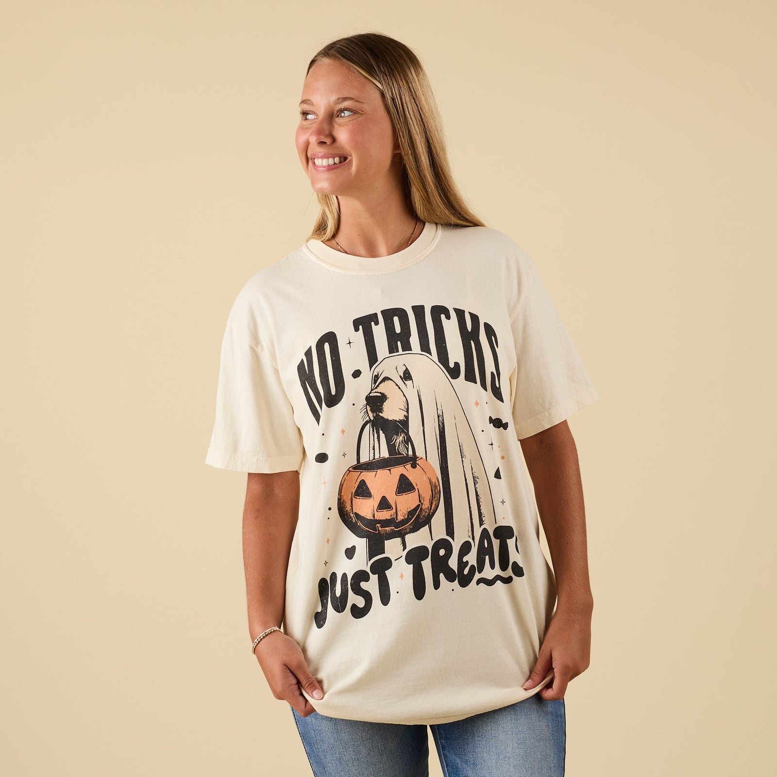 Front view of ivory graphic t-shirt with “No Tricks Just Treats” text and dog ghost holding pumpkin bucket.