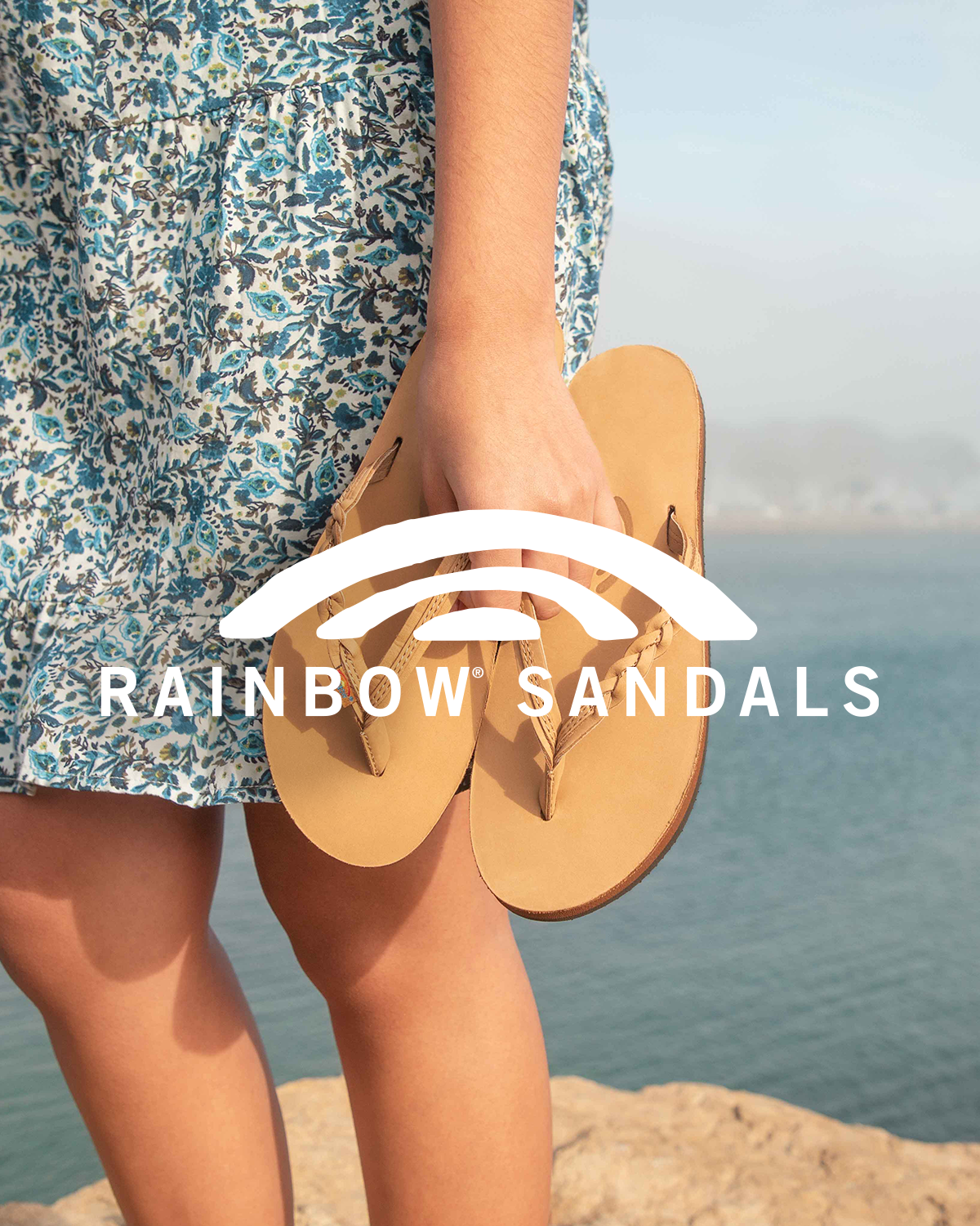 Woman holding a pair of Rainbow sandals.