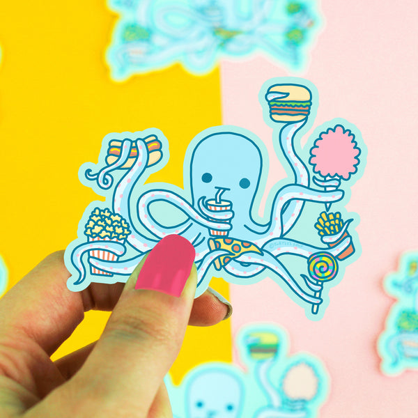 Hand holding a colorful octopus sticker against a multicolored background