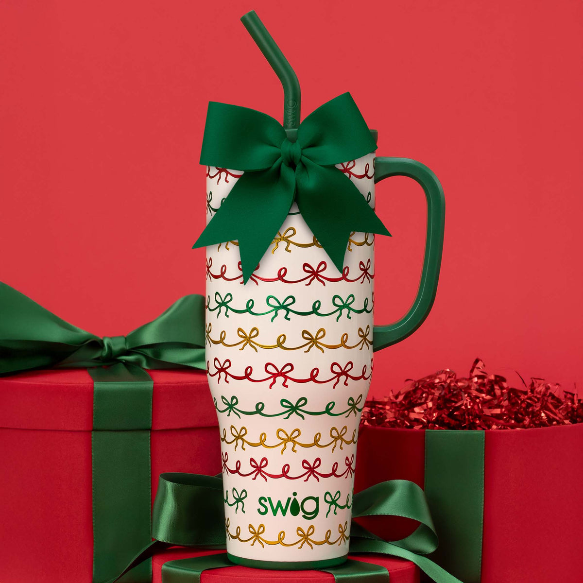 Decorative mug with green bow and 'swig' branding on a red background with gift boxes.