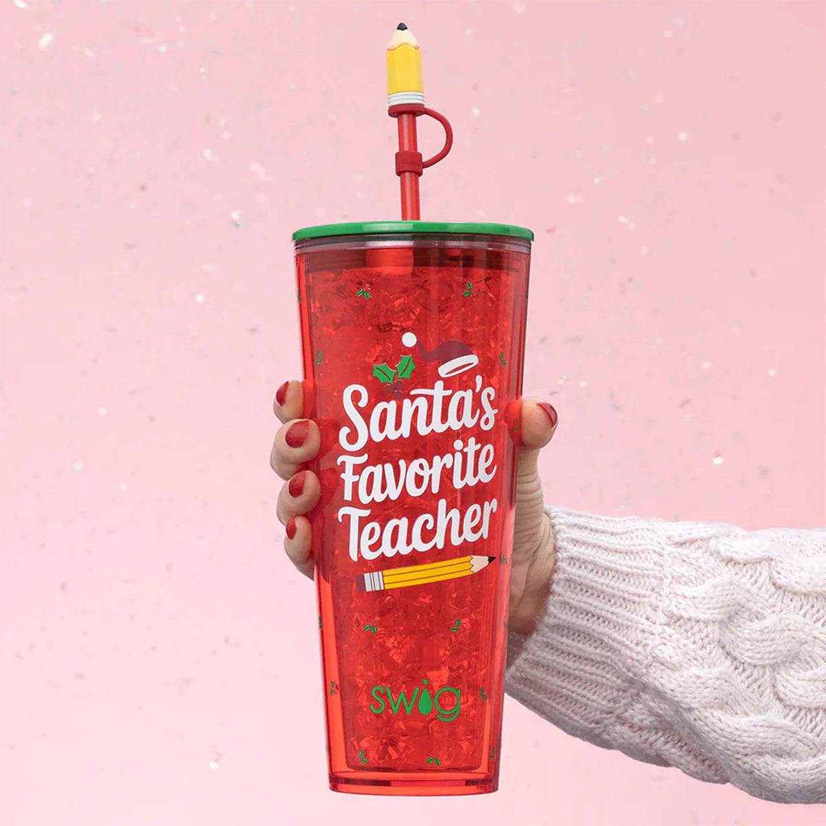Red Swig tumbler with 'Santa's Favorite Teacher' text held against a pink background